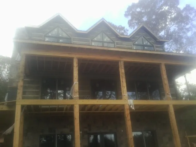 Dormers and porch framing on a large log home under construction — Roof Coating work by our crew in Monroeville