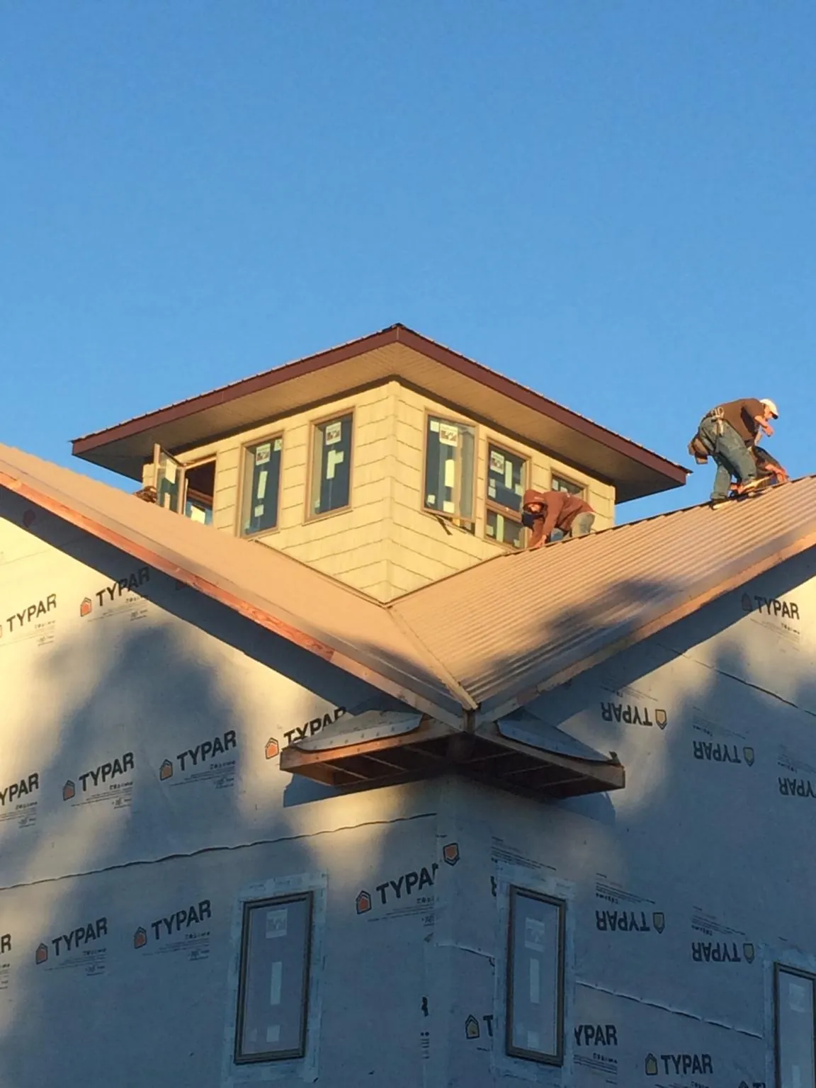 Roofers working around a rooftop cupola on a new metal roof at sunset — Roof Waterproofing in Monroeville by Roofing Brothers